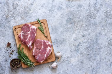 Tahtada şeritli biftek ve beton tabakta baharatlar. Yemek pişirmek için gerekli malzemeler.