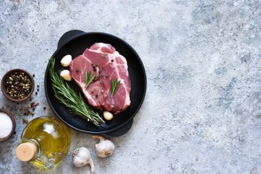 Beton arka planda baharatlı çiğ, çizgili biftek. Yemek pişirmek için gerekli malzemeler.