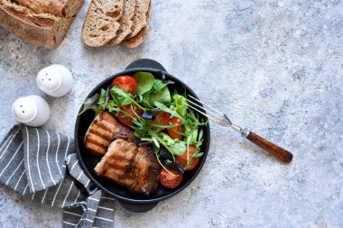 Beton arka planda tavada karışık salata ve sebzeli ızgara biftek..