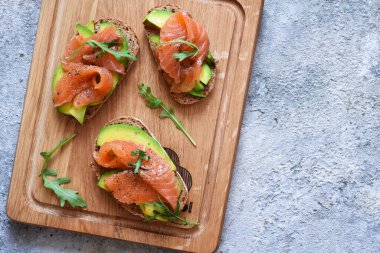 Tahta üzerinde avokado ve somonlu sandviç, üst manzara..