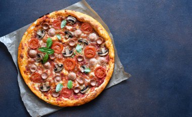 Domates soslu pizza, mantar ve peynirli esmer bir arka plan. Yukarıdan görüntüle.