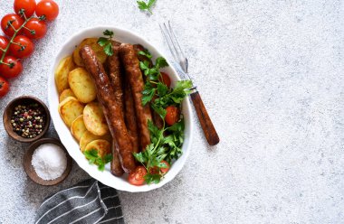 Beton zeminde patates ve sebzeli Bavyera sosisi. Yukarıdan görüntüle.