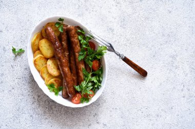 Beton zeminde patates ve sebzeli Bavyera sosisi. Yukarıdan görüntüle.