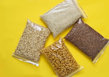 Sarı arka planda gıda bağışları: yağ, karabuğday, şeker, konserve yiyecek. Evinde otur. Karantina.