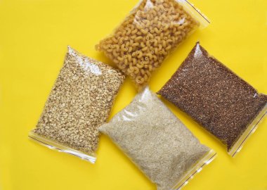 Sarı arka planda gıda bağışları: yağ, karabuğday, şeker, konserve yiyecek. Evinde otur. Karantina.