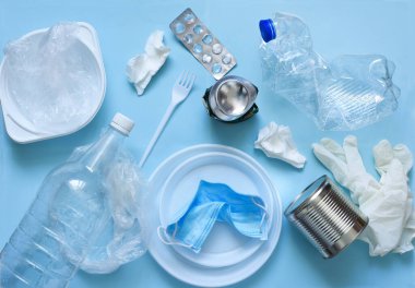 Mavi arka planda plastik çöp: tabaklar, şişeler, polietilen, maske. Çevre kirliliği. Ekolojik felaket.
