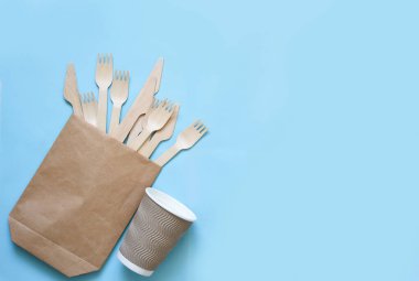 Tek kullanımlık eko-kağıt tabaklar: cam, karton, çanta, çatal, bıçak. Boş mavi bir arkaplanda. Geri dönüşüm kavramı.