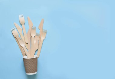 Tek kullanımlık çevresel eşyalar ve mavi arka planda bir bardak karton..