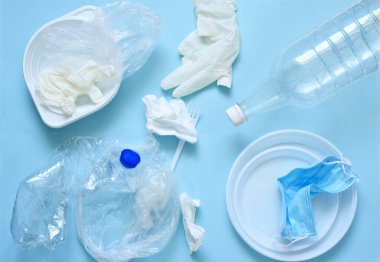 Mavi arka planda plastik çöp: tabaklar, şişeler, polietilen, maske. Çevre kirliliği. Ekolojik felaket. Mavi arka planda çöp düzeni.