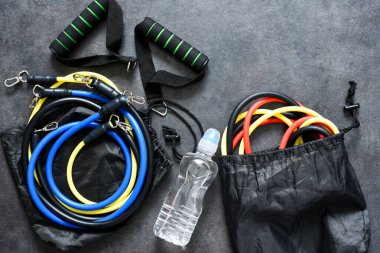 Sports accessories - an expander with a carbine and water on a black background. Fitness. clipart