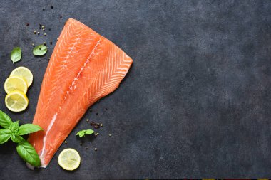Siyah arka planda limon ve fesleğenli çiğ somon filetosu. Düz yiyecek..