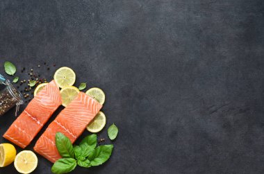 Siyah bir arka planda limon, fesleğen ve baharatlı somon fileto dilimi. Düz yiyecek.