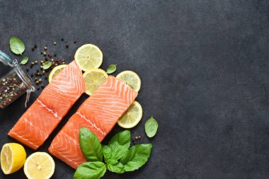 Siyah bir arka planda limon, fesleğen ve baharatlı somon fileto dilimi. Düz yiyecek.