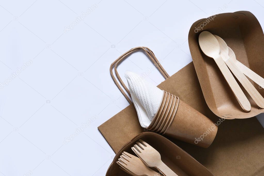 Paper bag with a picnic set: plate, fork, glass, napkins. Caring for the environment.Flatly.