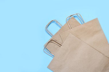 Mavi bir arka planda alışveriş için el işi kağıt torbaları. Düz. Hediye çantası.