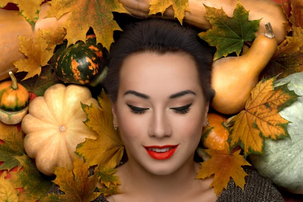 Die junge Frau auf dem Hintergrund von Herbstblättern und Kürbissen — Stockfoto