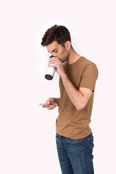 年轻的男人站杯热咖啡与电话 — 图库照片