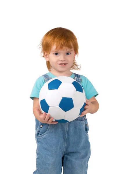 Das Kind mit den roten Haaren hält einen Fußballball in der Hand — Stockfoto