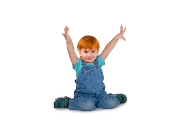 Дитина з рудим волоссям сидить на підлозі і сміється — стокове фото