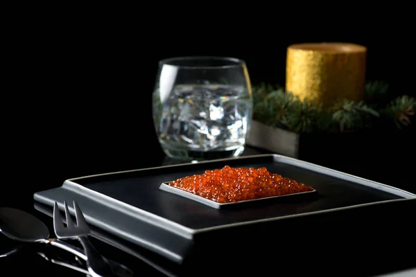 Caviar rojo se encuentra en un plato negro elegante de cerámica cuadrada —  Fotos de Stock