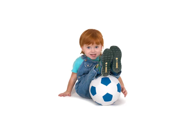Das Kind mit den roten Haaren turnt mit dem Fußball — Stockfoto