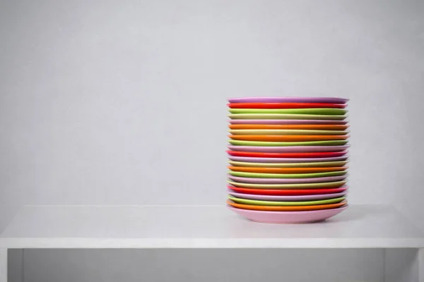 La pila di piatti a colori si trova su un tavolo — Foto Stock