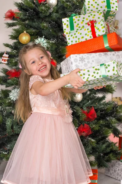 在圣诞树上的女孩手持礼物的盒子 — 图库照片