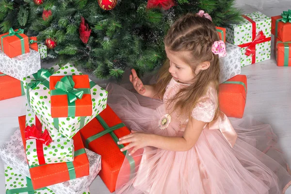 Criança menina assistir presentes sob uma árvore de Natal . — Fotografia de Stock