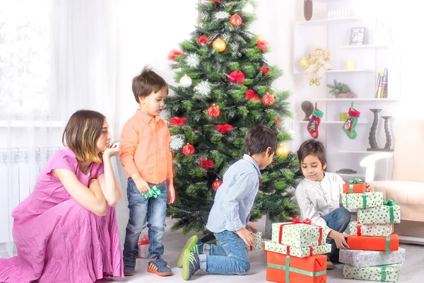 男孩手里拿着许多礼物在一棵圣诞冷杉树 — 图库照片