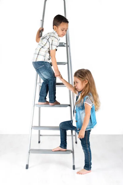 A fiú segít a lánynak, hogy emelkedik a létrán — Stock Fotó