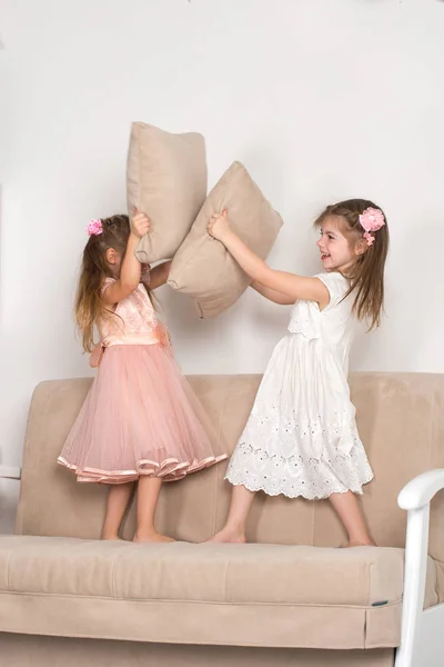 女の子二人はソファにジャンプし、枕の元気再生されます。 — ストック写真