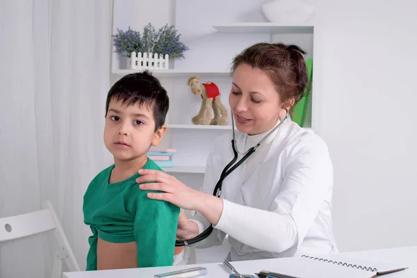 El médico examina al niño enfermo escolar en un consultorio — Foto de Stock