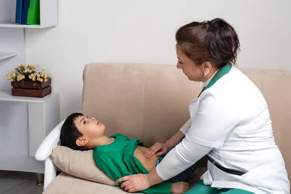 El médico wonan examina al niño enfermo escolar en una clínica — Foto de Stock