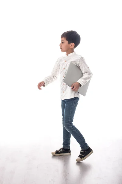 Хлопчик в джинсах і футболці з ноутбуком йде — стокове фото