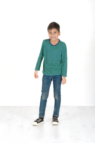 El chico en jeans y una camiseta a rayas se para y sonríe — Foto de Stock