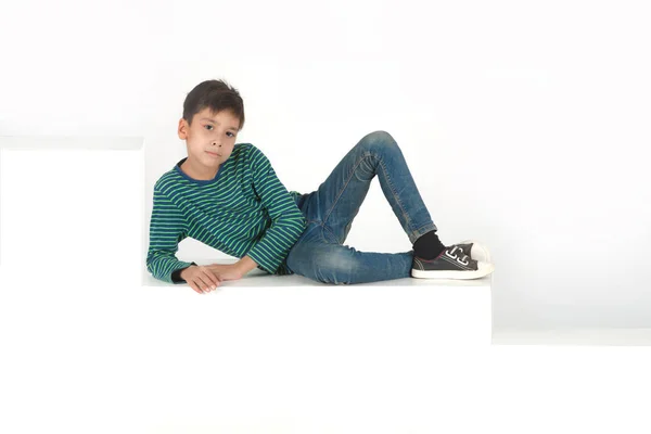 Мальчик сидит на белых ступеньках или коробках — стоковое фото