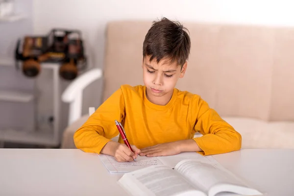 Skolpojke brunett bär gul t-shirt studien hemma för skolan i rummet — Stockfoto
