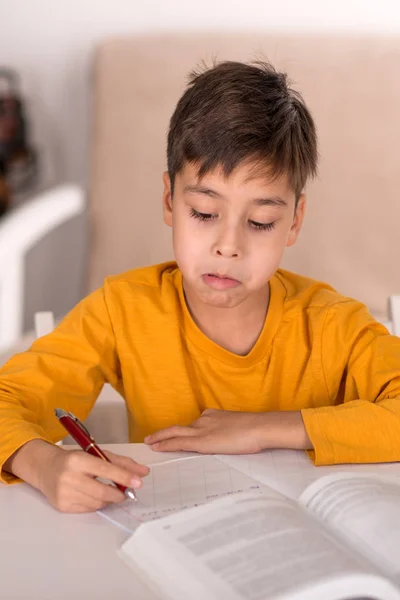 The schoolboy of brunette wearing yellow t-shirt study at home for school in the room — Stock Photo, Image