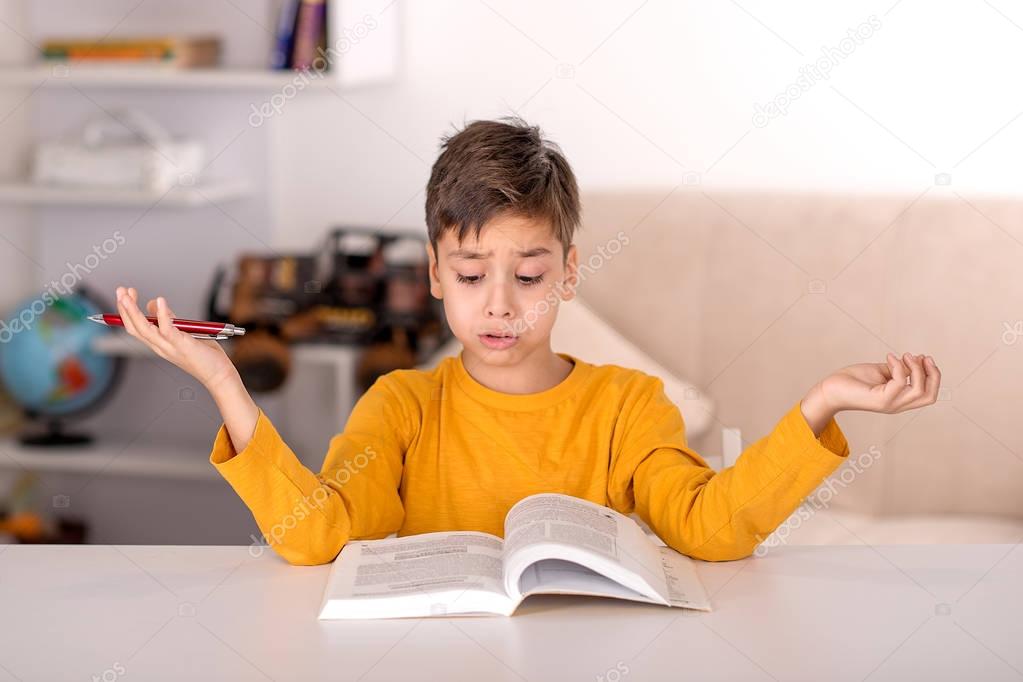 The schoolboy of brunette wearing yellow t-shirt study at home for school in the room