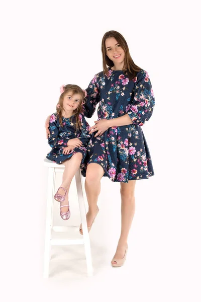 母亲与女儿在相同的礼服站立和微笑在白色背景在演播室 — 图库照片