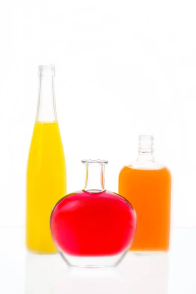 Três garrafas com álcool em uma mesa com a surfa refletora — Fotografia de Stock