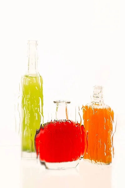 Three bottles with color drinks  stand on the reflecting surface — Stock Photo, Image
