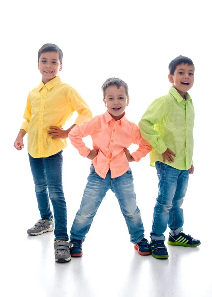 Drie jongens in een shirt en spijkerbroek staan op witte achtergrond in de studio — Stockfoto