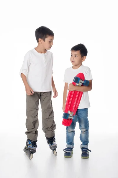 Två pojkar åker rullskridskor och en styrelse. — Stockfoto