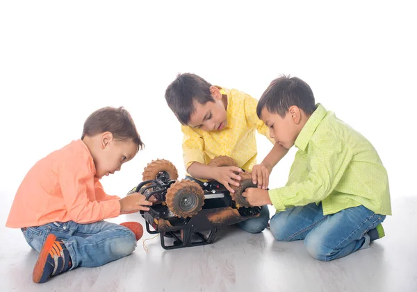 Троє хлопчиків з ентузіазмом ремонтують іграшковий автомобіль — стокове фото