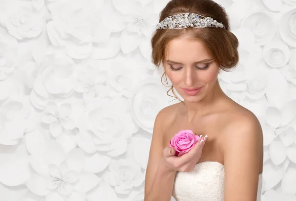 Bruden i ett halsband från pearls ser på en ros blomma — Stockfoto