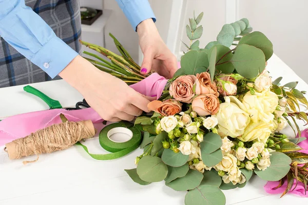 Die Floristin die junge Frau sammelt einen Strauß Rosen und de — Stockfoto