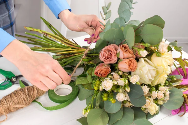 De bloemist de jonge vrouw verzamelt een boeket van rozen en de — Stockfoto