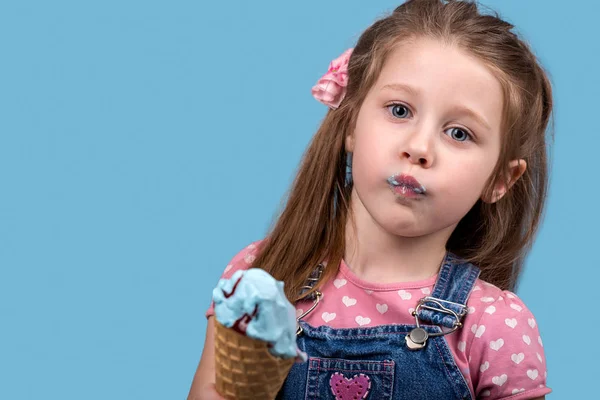 A kislány eszik fagylaltot ostya juta, a kék backgro — Stock Fotó