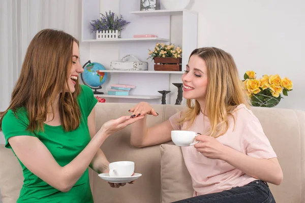 Two young attractive women sit on a sofa in the room and I talk — Stock Photo, Image
